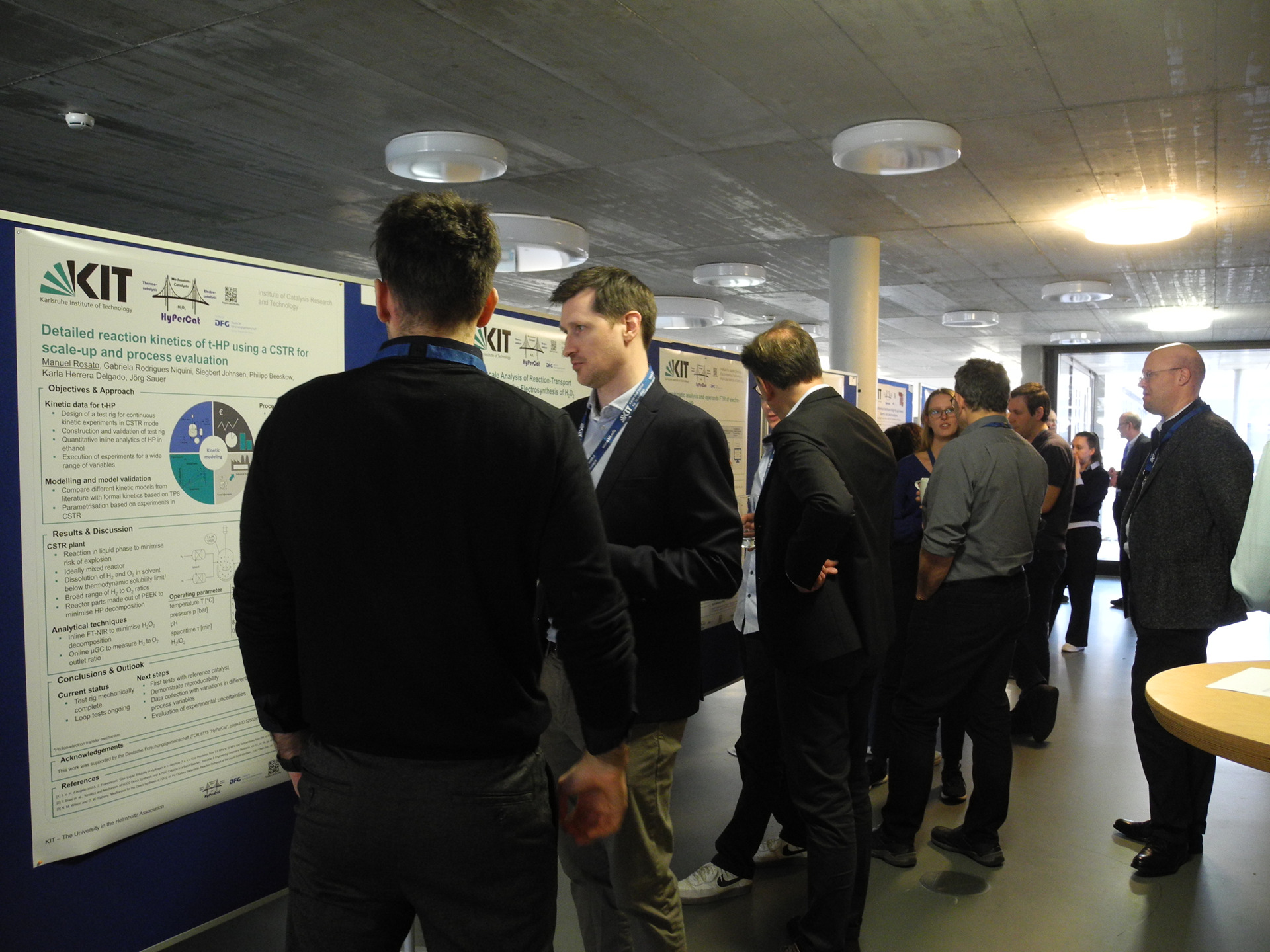 Menschen bei einer Posterpr&auml;sentation im Konferenzzentrum, mehrere Posterreihen.