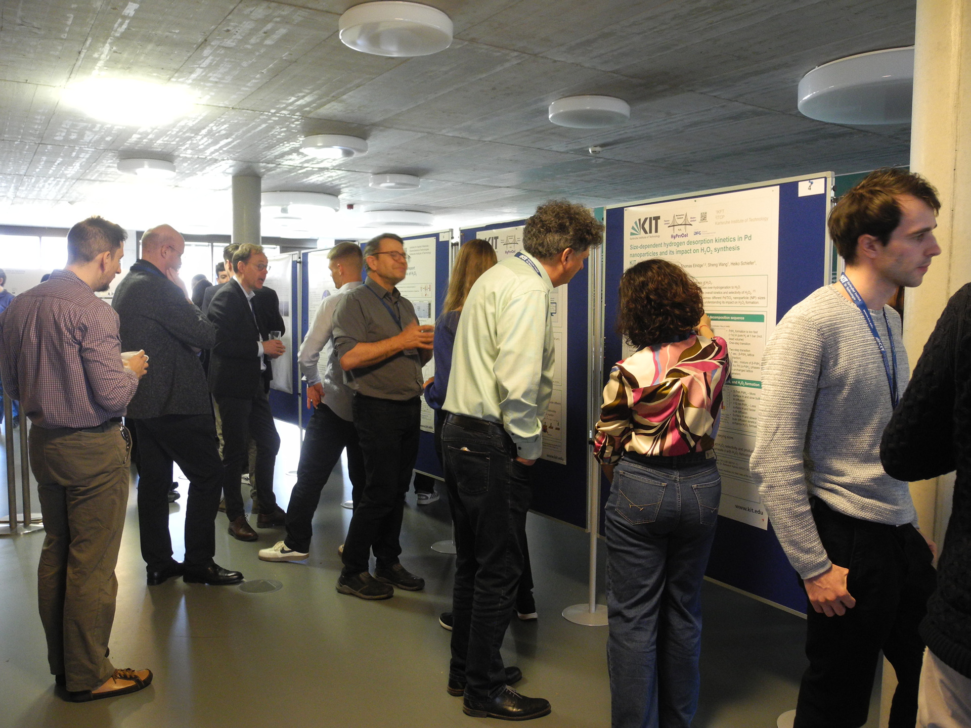 Gruppe von Fachleuten bei Posterpr&auml;sentationen in einer Konferenzhalle.