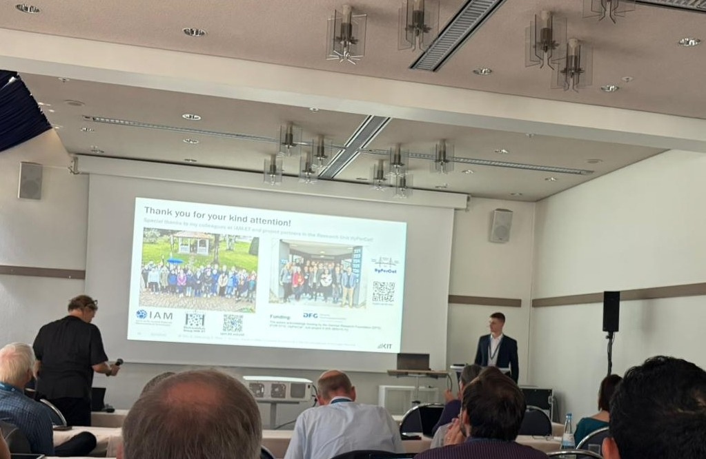 Vortragender vor einem Publikum mit einer Abschlussfolie einer Präsentation in einem Seminarraum.